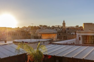 City landscape at sunset with a view of rooftops and a tower in the background