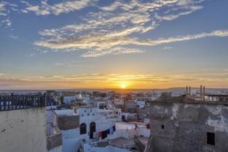 City panorama at sunrise with warm sky tones and scattered clouds over flat buildings