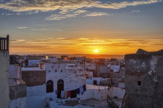 View of a city at sunrise with warm light and clouds in the orange sky