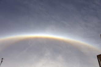Glowing semicircular halo on cloudy sky