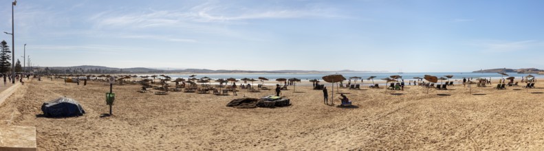 Extensive sandy beach with umbrellas on a clear blue sky