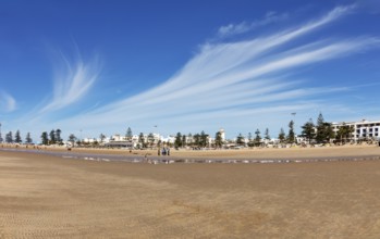 Wide sandy beach with townhouses and dramatic cloudy skies