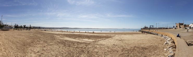 Panoramic view of a wide sandy beach next to the sea under clear skies