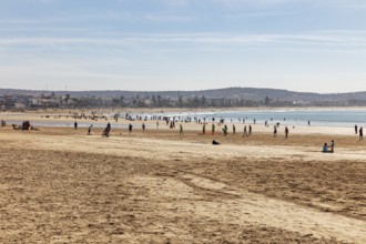 People frolic on the sandy beach with views of the vast sea and the blue sky