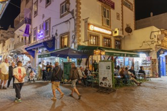 Nightlife on a busy alleyway with cafes and people in an alley