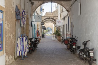 Narrow alley with arches, hanging clothes and parked bikes during the day