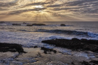 Dramatic cloud formations and sunbeams over the sea at sunset