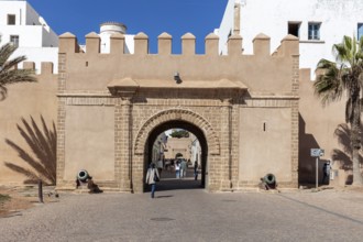 Historic city gate with archway and people, illuminated by daylight