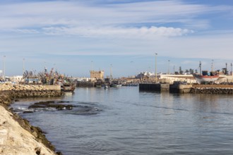 View of a quiet harbor with water, docked boats and a fort in the background