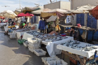 Market scene with fish stalls and vendors, colorful umbrellas and people in a peaceful atmosphere