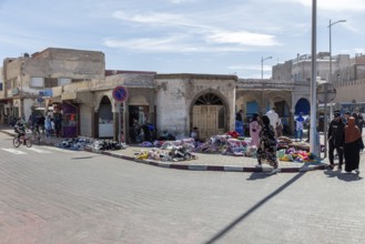 Lively street scene with market stalls and people in a sunny city