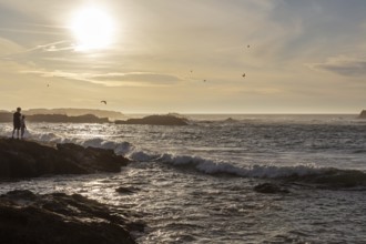 Romantic coastal scene with sunset and silhouettes on the seashore