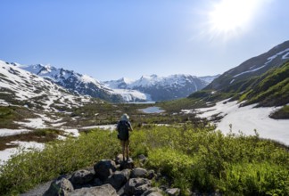 Hiker enjoys views from Portage Pass of Divide Lake, snowy mountain peaks and glaciers Portage