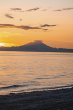 View of Cook Inlet on white mountain peaks of Mount Redoubt at sunset, picturesque golden light of