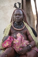 Baby in the arms of a Himba woman, traditional Himba village, Kaokoveld, Kunene, Namibia