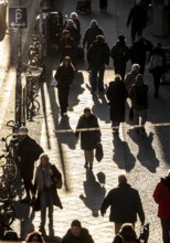 Passers-by on a Friedrichstraße sidewalk in Berlin, shade, low sun, winter, Germany