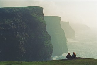 People on the edge of a cliff, there was no fence back then, Cliffs of Moher, County Clare,