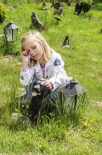 Grieving blonde 7-year-old girl at her dog's grave at pet cemetery in Ystad, Skåne County, Sweden,