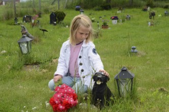 Grieving blonde 7-year-old girl at her dog's grave at pet cemetery in Ystad, Skåne County, Sweden,