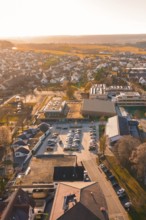 Aerial view of a village at sunset with parked cars and houses, sports center and swimming pool