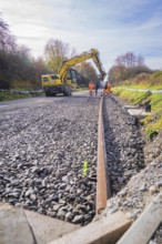 Crane aligning ballast on a construction site, workers watching, Hermann Hesse Railway track