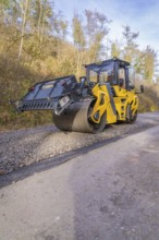Yellow road roller on a construction site surrounded by autumn trees, Hermann Hesse Railway track