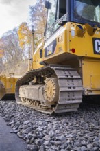 CAT chain tractor on gravel, area in autumn forest during construction, Hermann Hesse Railway track
