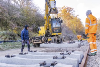 Track construction with a yellow excavator, where workers lay heavy concrete ties, Hermann Hesse