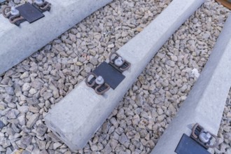 Detailed view of concrete sleepers and their metal fastenings on gravel, track construction of the