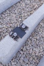 Close-up of a concrete threshold with fasteners on gravel, track construction of the Hermann Hesse