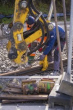 Construction workers work together on rails with heavy equipment, track construction of the Hermann