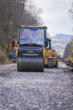 Bomag road roller rolls over gravel for compaction during road work, Hermann Hesse Railway track