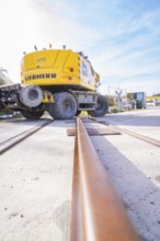LIEBHERR excavator near rails, blue sky perspective, track preparation, Hermann Hesse Railway track