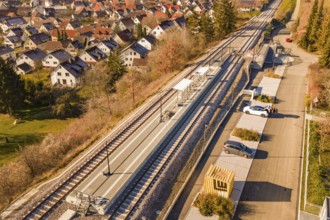 Aerial view of a village with a small train station surrounded by houses and autumn vegetation, new