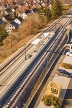 Aerial view of a small train station with parked cars surrounded by autumn vegetation and a