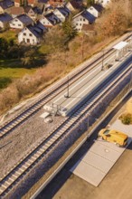 Small train station in a village with adjacent houses and trees, taken from the air, new Hermann