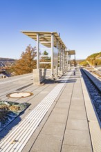 Busy platform in autumn sunlight with modern structures, new Hermann Hessebahn railway station,