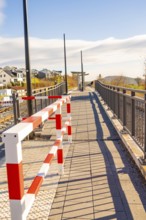 Footbridge with modern barrier and cast shadows in sunshine, new Hermann Hessebahn railway station,