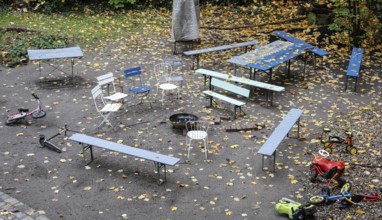 Chairs and tables stand unsorted around a fire bowl, a celebration in the garden is over, colorful