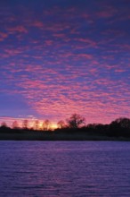 Intense sunset with dramatically colored sky over the river, Peenetal nature park Park,