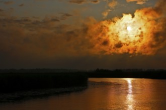 Dramatic cloud formation at sunset reflected in a calm river, Peenetal nature park Park,