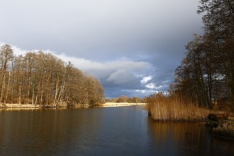 Spring atmosphere with cloudy skies and sunshine over a quiet river, Peenetal nature park Park,