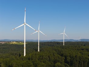 Several wind turbines stretch into the sky over an extensive forest area, near Schorndorf, Remstal,