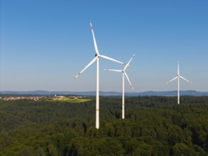 Three wind turbines above a dense forest area under a clear sky, near Schorndorf, Remstal,