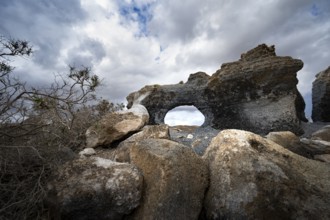 Eroded rock formations with rock tunnels, volcanic landscape with dramatic cloudy skies, Ciudad