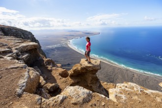 Woman enjoying the view from the Risco de Famara cliffs on Famara beach, Playa de Famara with La