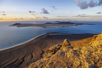 View of steep cliffs to sea and the island of La Graciosa, Mirador del Porrito viewpoint at sunset,