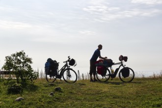 Two e-bikes with luggage bags, cyclist taking a break, back light, Ystad, Sweden