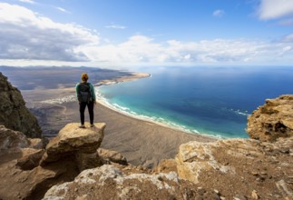 Young woman enjoying the view from the Risco de Famara cliffs to Famara beach, Playa de Famara with