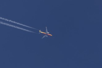 Boeing 767 jet cargo aircraft of DHL airlines flying in a blue sky with contrails or vapours trails